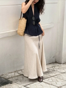 Detail of elegant navy V-neck halter top paired with a beige linen maxi skirt in sunlight