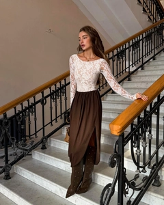 Detail of elegant white lace long-sleeved top paired with high-slit brown midi skirt