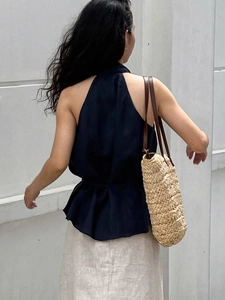 Elegant navy halter neck top with ruffled waist paired with a linen skirt and straw bag