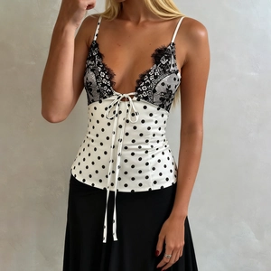 Close-up of elegant V-neck satin camisole with black lace trim and polka dot pattern