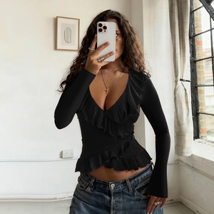 Detail of black V-neck wrap top featuring ruffled edges and slim-fit long sleeves
