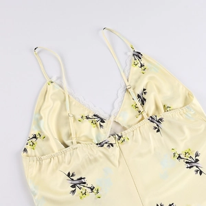 Détail du col en V avec bordure en dentelle blanche sur une robe d'été jaune fleurie