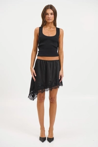 Dettaglio gonna asimmetrica in raso nero con bordo in pizzo delicato e trama in chiffon