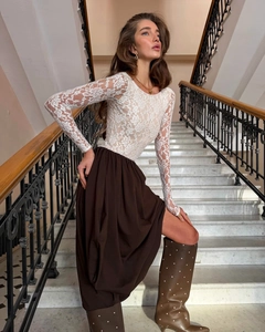 Close-up of white lace slim-fit long sleeve top with intricate floral pattern texture