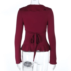 Detail of the ruffle hem and adjustable back tie-up bow on this burgundy long sleeve top