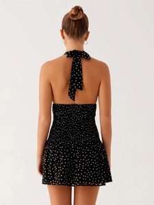 Back view of a polka dot halter neck dress with open back and smocked waist detail