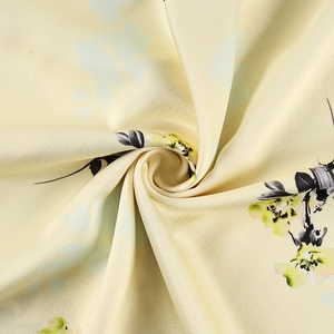 Vue détaillée du tissu en soie haut de gamme avec motifs floraux jaunes et verts élégants