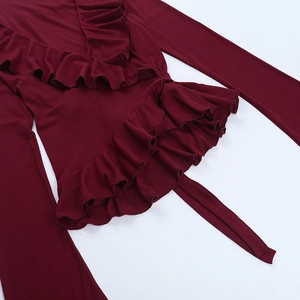 Detailed close-up of dark red long-sleeve top with ruffled edges and tie-waist design