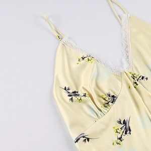 Détail de la dentelle en V et de l'imprimé floral sur la robe en satin jaune