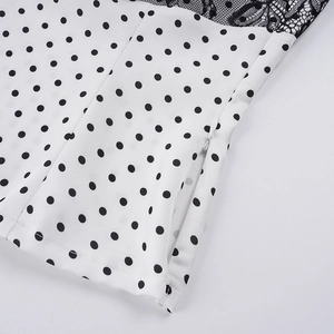 Detail of white polka dot satin top with black floral lace and hidden side zipper