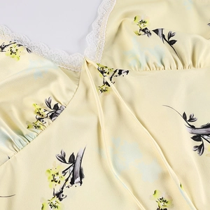 Détail d'une robe fleurie jaune montrant la dentelle délicate et le nœud au décolleté