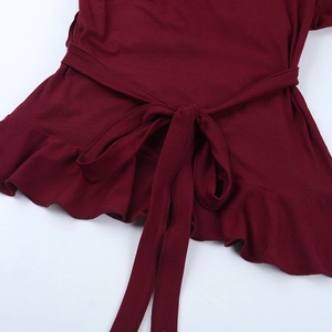 Detail of burgundy top showing adjustable bow tie waist and elegant ruffled hemline