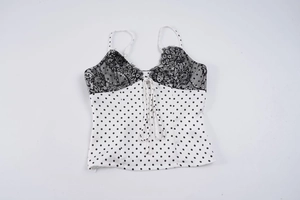 Detail of white polka dot camisole with black lace neckline and front drawstring tie