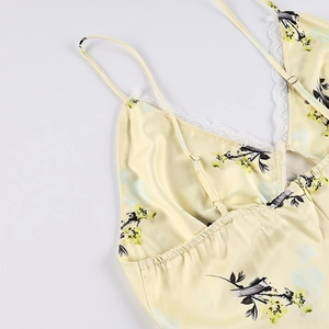 Détail d'une robe fleurie en satin jaune avec bordure en dentelle blanche et bretelles