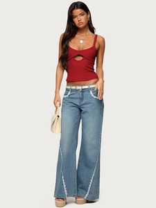 Detail view of red knit tank top with cutout and lace-trimmed jeans on a model