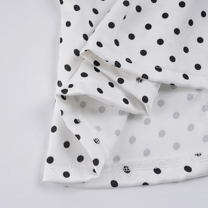 Detail view of polka dot satin fabric with V-neck lace trim and neat double-needle stitching