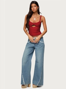 Detail of red ribbed crop top with crescent cutout and lace-trimmed denim pants
