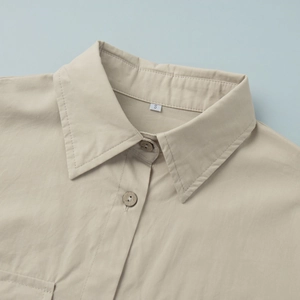 Close-up of beige cotton shirt collar featuring wooden buttons and S-size label