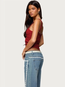 Red ribbed camisole with blue lace-up denim jeans set on minimalist background