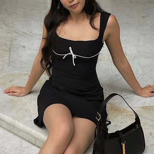 Detalle del vestido corto negro ajustado con ribete blanco y lazo en el escote cuadrado