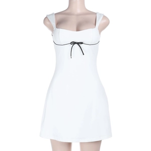 Detalle de minivestido blanco ajustado con lazo negro decorativo y ribetes de diseño