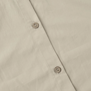 Detail of cotton fabric texture and two brown buttons on the beige casual shirt set
