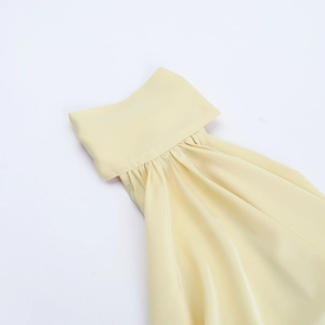 Dettaglio ravvicinato della scollatura dell'abito giallo chiaro con texture in chiffon a pieghe