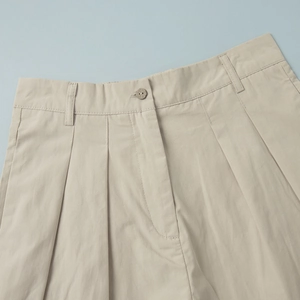 Detail of cotton shorts waist with button, pleats and beige twill fabric texture