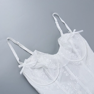 Detail of white floral lace bodysuit with adjustable straps and small bow accents