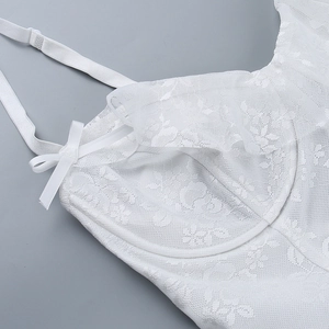 Close-up of white lace bodice featuring floral patterns and delicate ribbon bow details