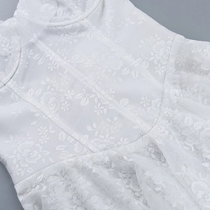 Detailed view of intricate white floral lace fabric and mesh texture on the dress