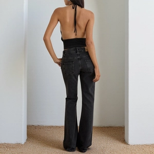 Detail view of denim jeans back pockets and waist leather patch with a fitted black top