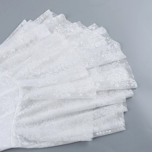 Detail of white lace dress showing multi-layered scallop embroidery and floral mesh texture