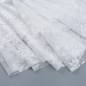 Close-up of white floral lace fabric with intricate mesh base and delicate patterns