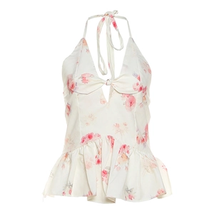 Detail of floral halter top featuring a bow cutout and ruffled hem on white fabric