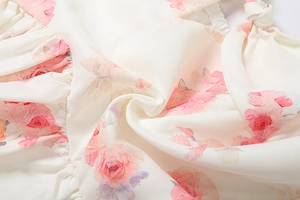 Detail of floral chiffon fabric with pink rose prints and ruffled pleats on dress