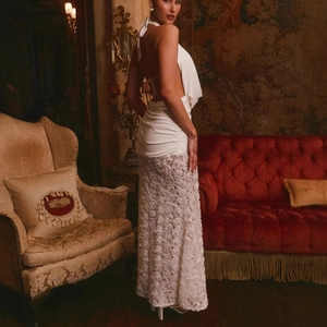 Detail of white backless halter dress featuring 3D rose lace skirt and slim pleated waist