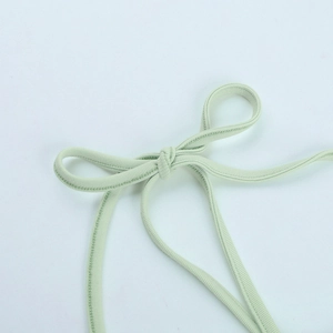 Detail view of mint green ribbed fabric texture and a neatly tied bow on the shoulder strap