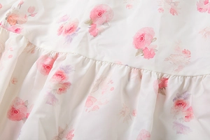 Macro view of white chiffon dress fabric with pink roses and pleated stitching details
