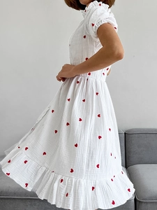 Close-up of white summer dress with red heart prints and ruffled hemline textures