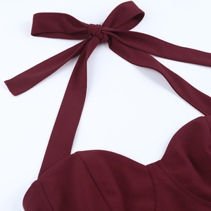 Macro view of burgundy dress with halter neck tie and large structured bow detailing