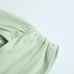 Close-up of light green ribbed knit fabric featuring detailed ruched seam design