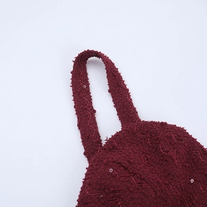 Macro shot of burgundy sequined fabric with textured weave and wave stitching details