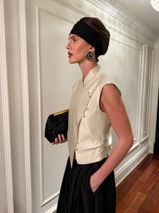 Detail of elegant cream sleeveless top with traditional Chinese side buttons and satin finish