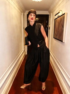 Detail of a chic black sleeveless high-neck top with traditional buckle and harem trousers