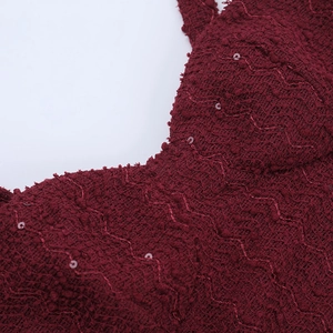 Detailed macro view of dark red glitter fabric with wavy texture and shimmering sequins