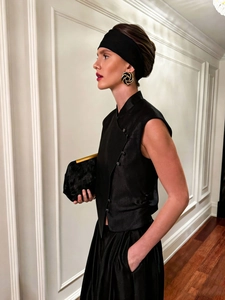 Detail of a chic black sleeveless vest with traditional knot buttons and satin finish