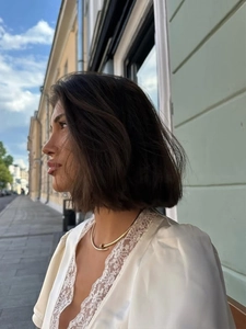 Dettaglio di una moderna collana a chiodo dorata indossata in luce naturale esterna