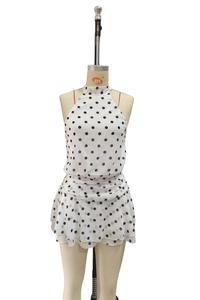 Detail of white polka dot halter dress featuring shirred waist and tiered chiffon skirt