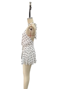 Detailed side view of white polka dot halter dress with backless cut and ruffled hemline
